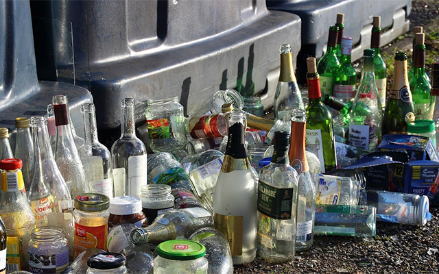 leere Glasflaschen vor Müllcontainern