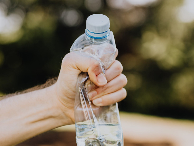 Eine Hand zerquetscht eine Plastikflasche