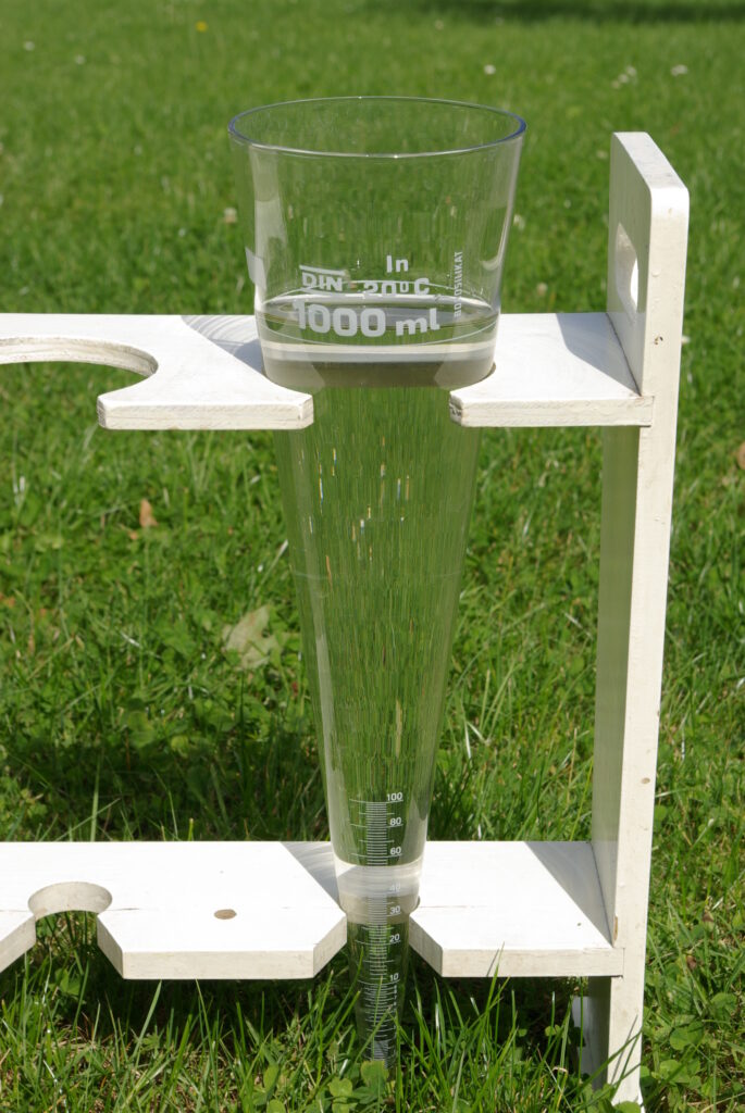 Ein Glastrichter, der mit klarem Wasser gefüllt ist, steht in einem Ständer auf einer Grasfläche