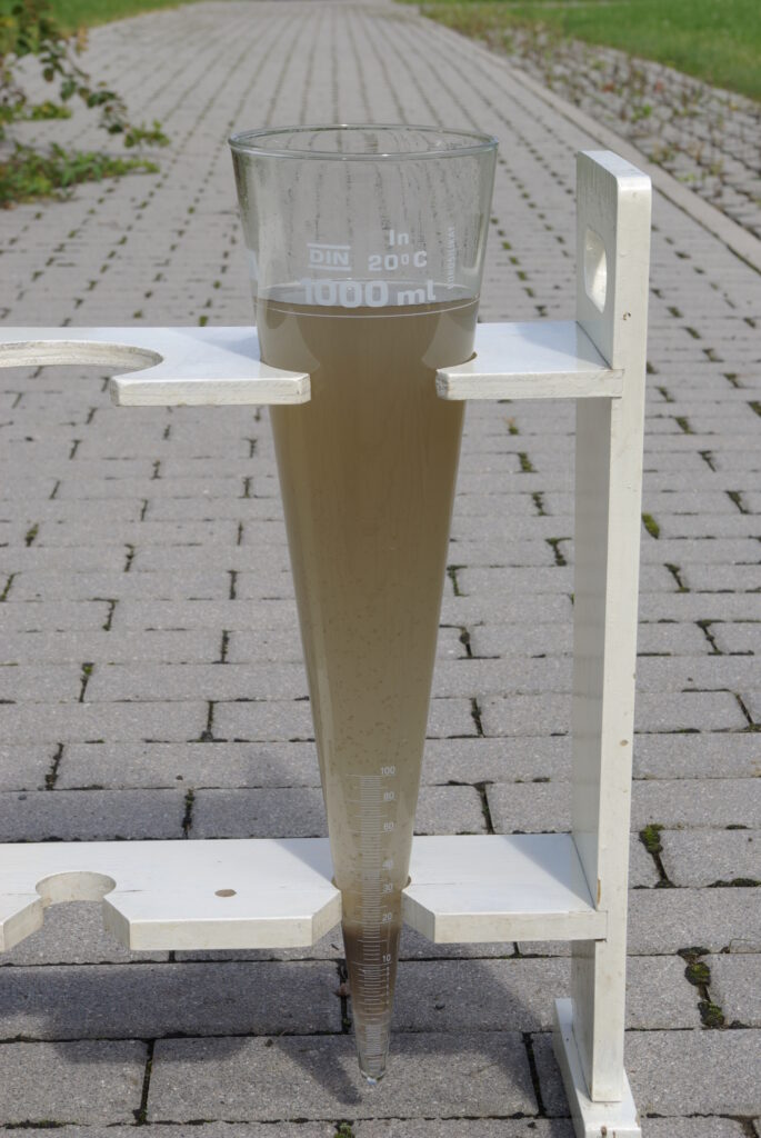 Ein Glasbehälter, der mit verschmutztem Wasser gefüllt ist.