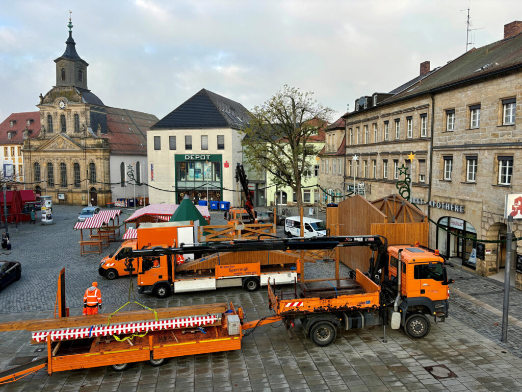 Mitarbeiter des Stadtbauhofs bauen auf dem Marktplatz mit Hilfe von Kränen eine Bühne auf.